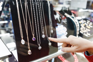 Woman’s hand pointing at jewelry in glass display case