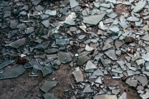 Shattered window glass shards strewn on the cement ground