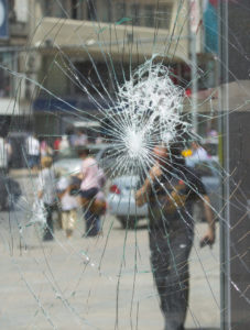 Man's reflection in a broken glass window