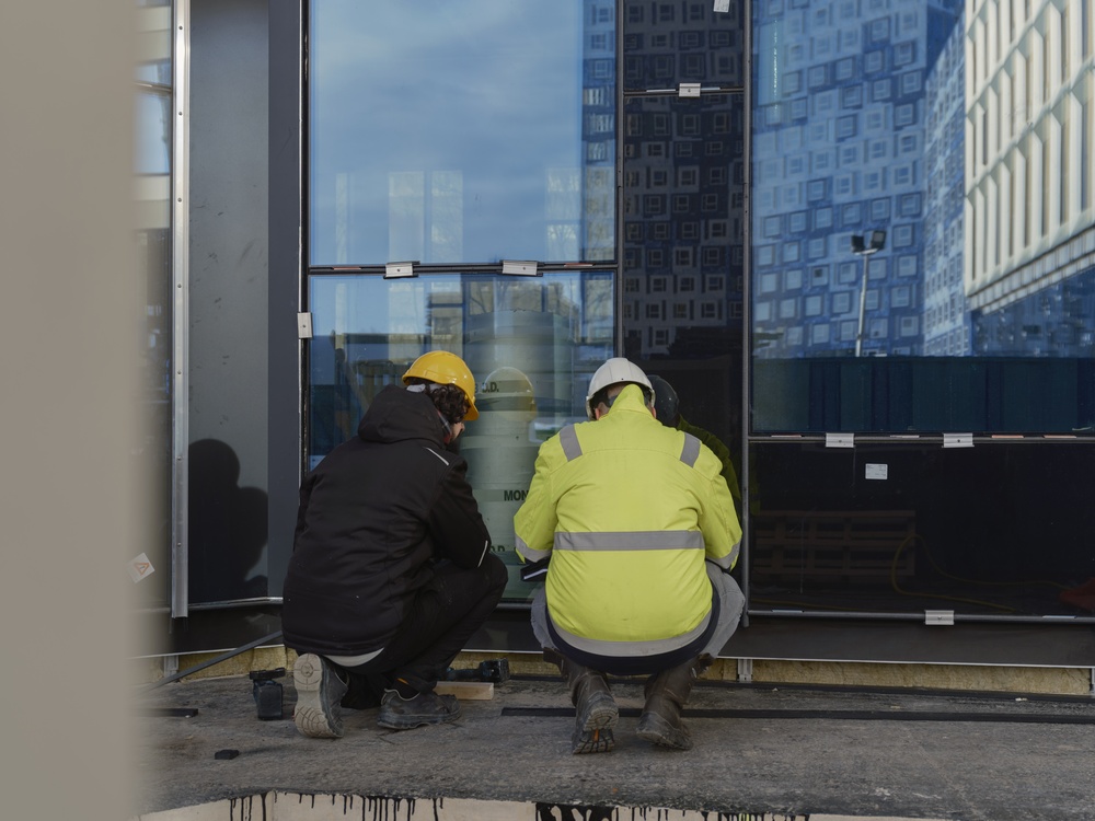 Workers fitting commercial glass panels onto a building