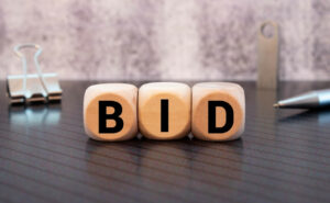 three wooden letter blocks saying BID