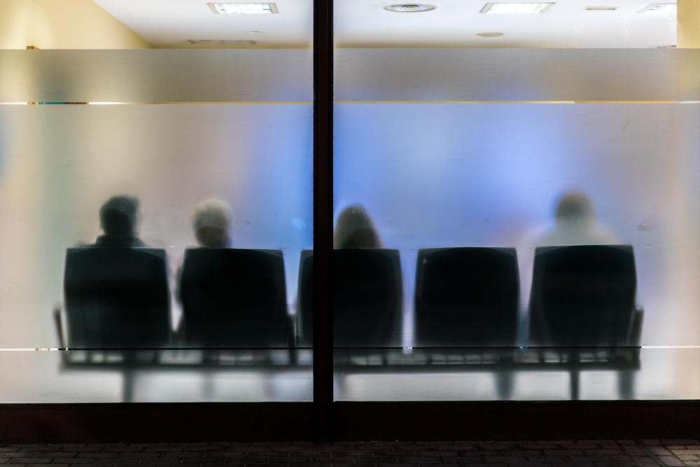 Silhouettes of people sitting in chairs behind privacy glass